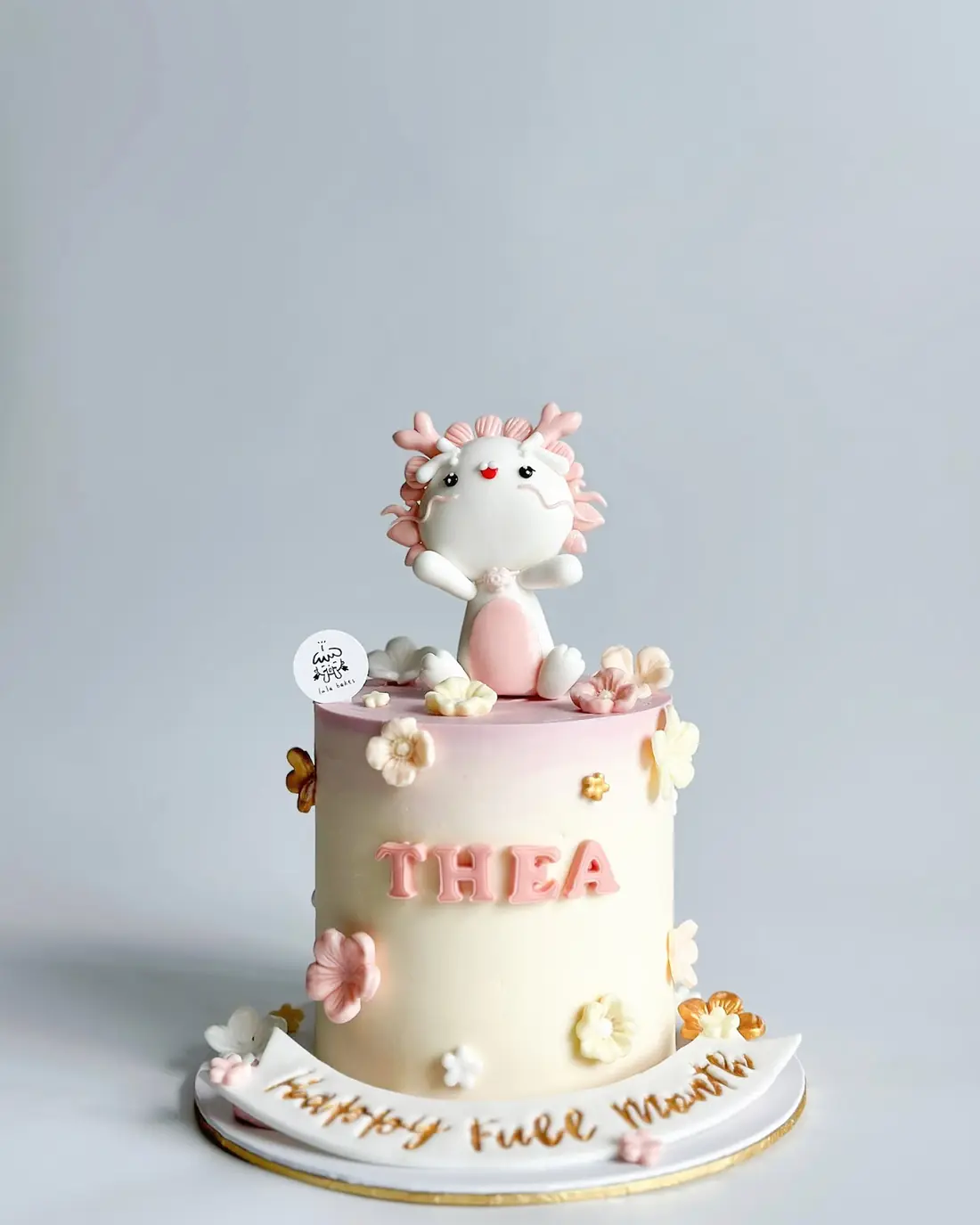 Pink full-month cake with a white bunny topper and sugar flowers