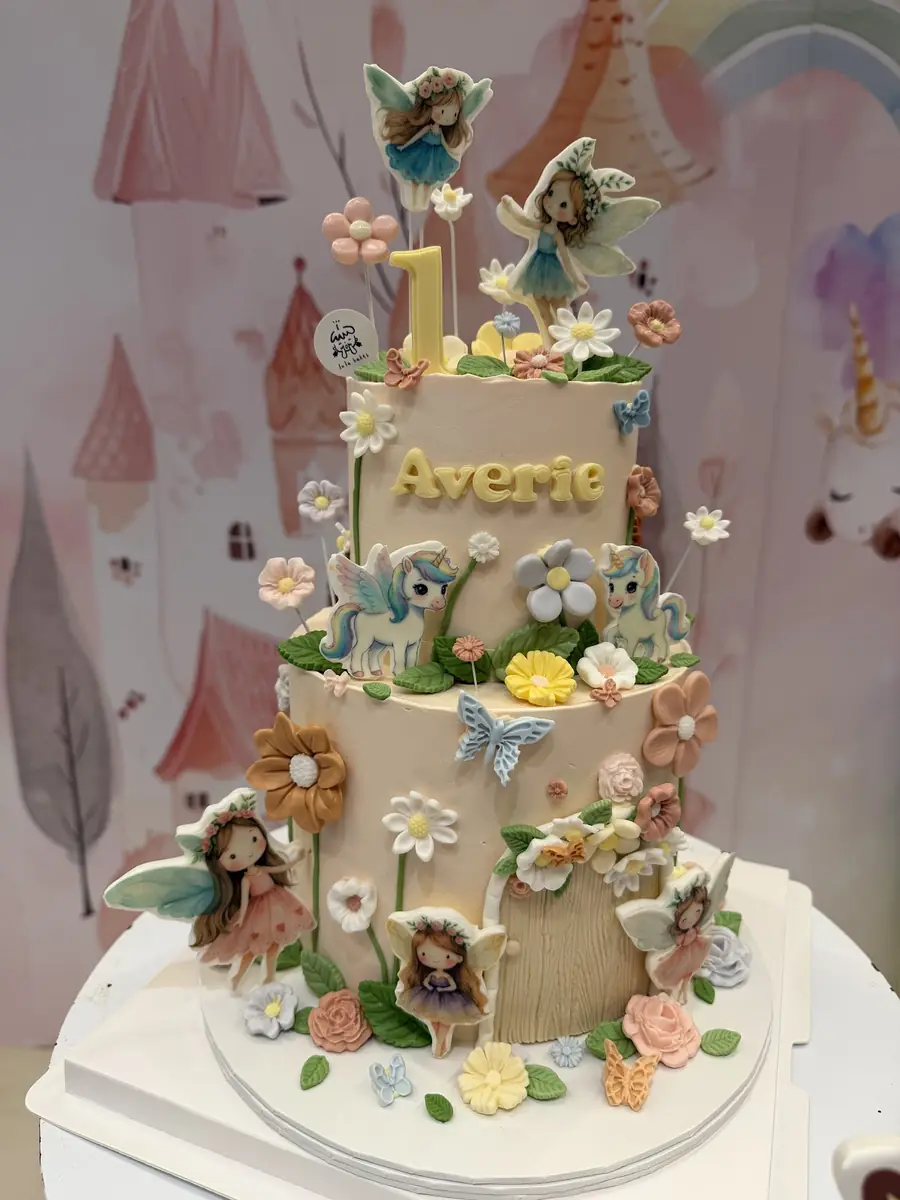 Two-tier fairy garden birthday cake with fairies and flowers