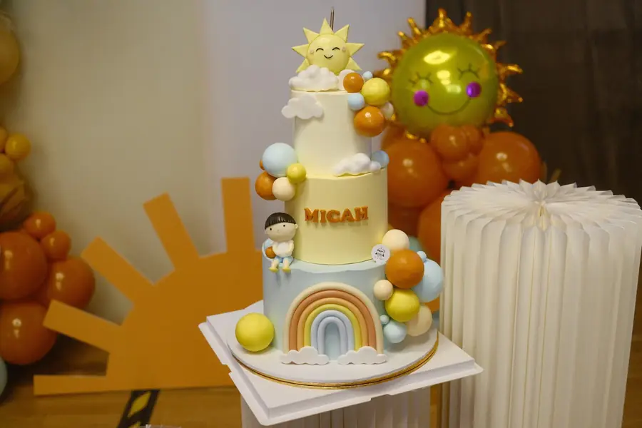 Two-tier rainbow and sunshine first birthday cake