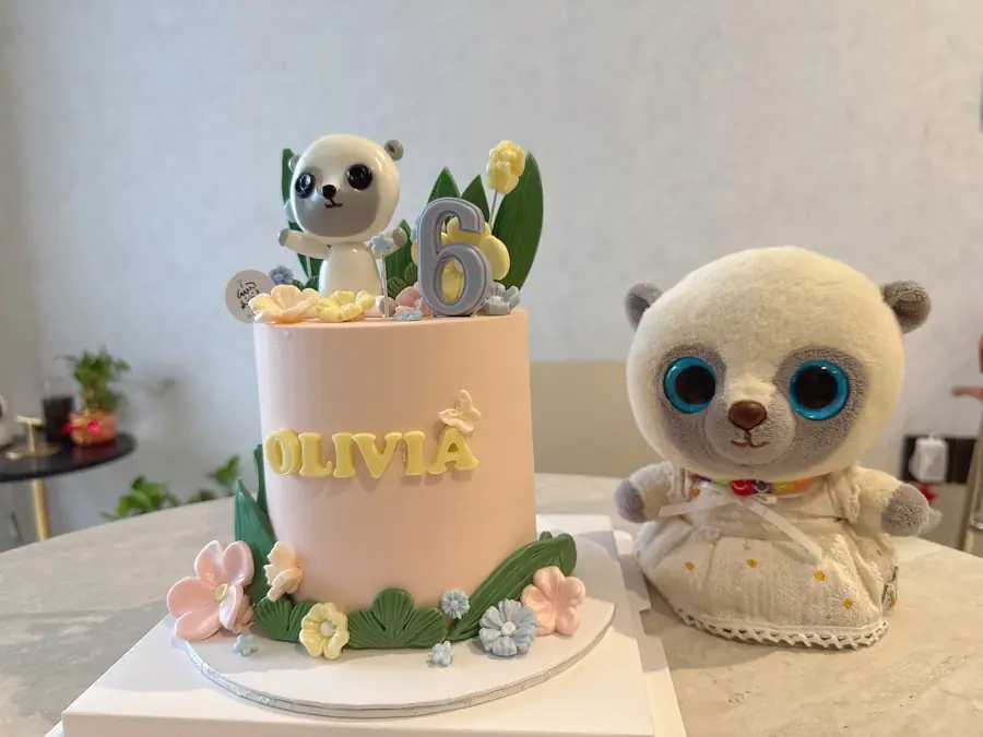 Pink birthday cake with a koala topper and flowers